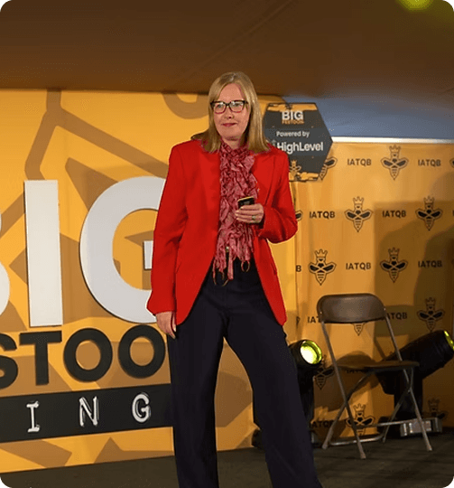 Speaker in a red jacket presenting on stage